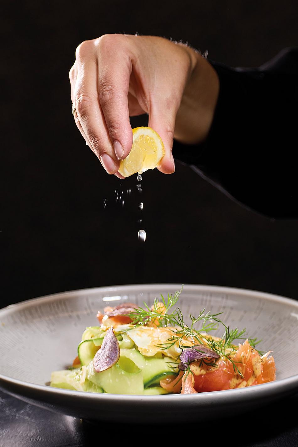 Eine Frau garniert ihr Essen mit einer frischen Zitrone