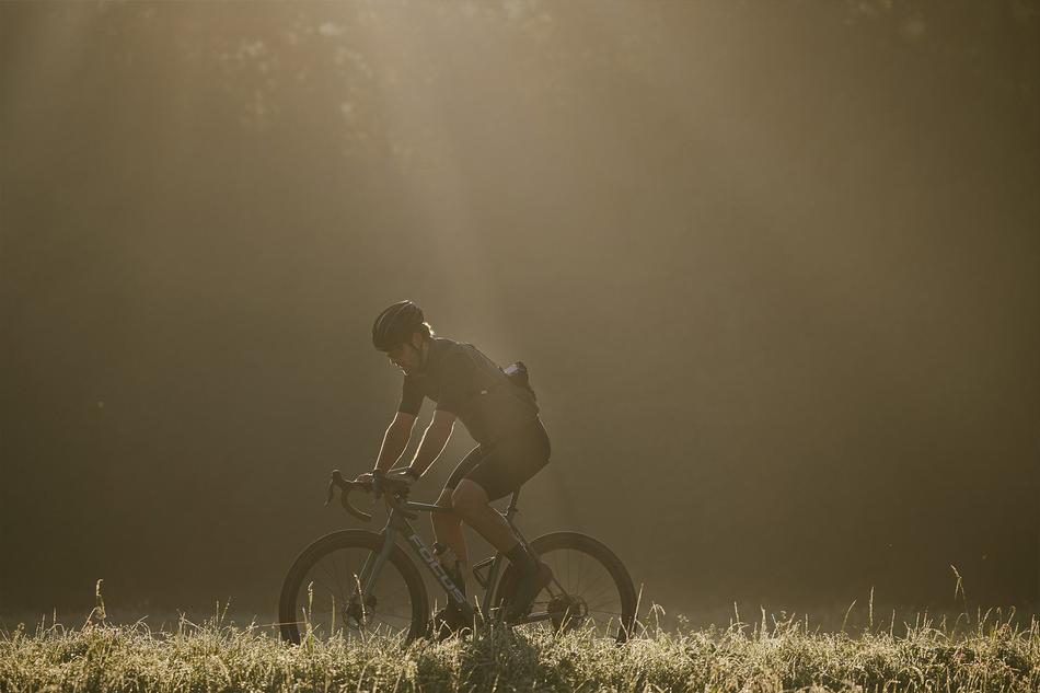 Ein Mann fährt am frühen Morgen mit seinem Fahrrad durch taubedeckte Wiesen