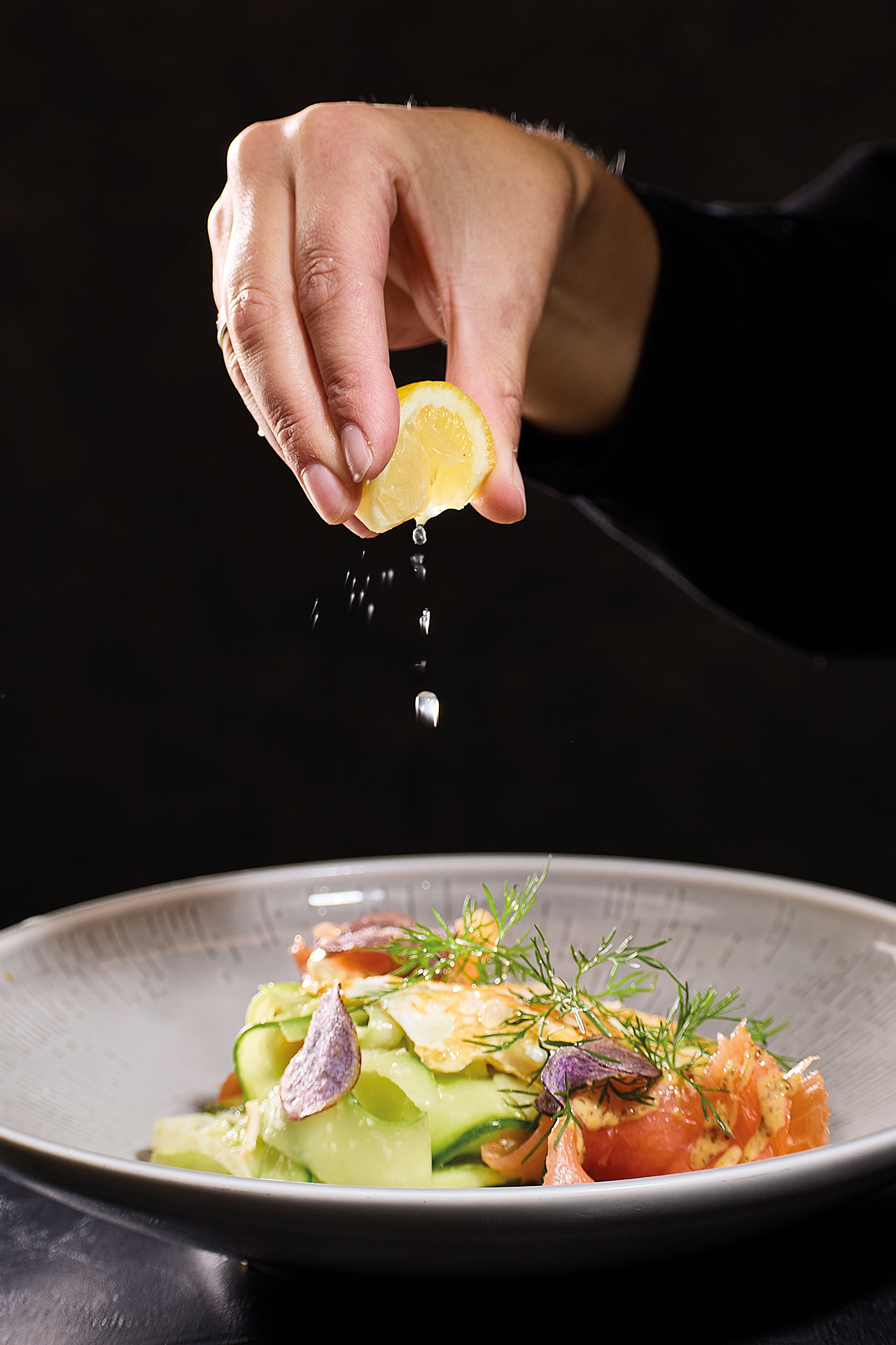 Eine Frau garniert ihr Essen mit einer frischen Zitrone