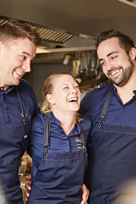 Drei Köche lachen herzlich in der Küche und haben Spaß