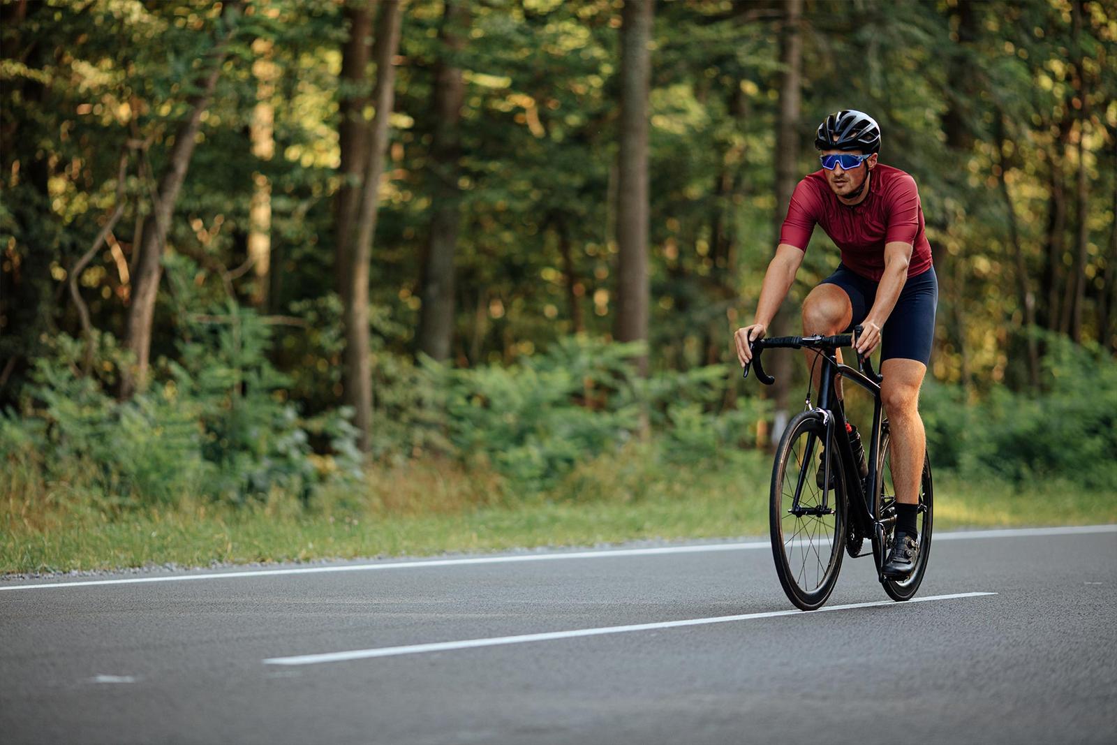 Ein Mann fährt mit seinem Rennrad auf einer Straße durch den Wald