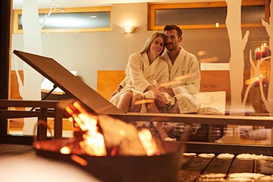 Ein paar genießt eine Auszeit im Außenbereich des Spa Bereichs an einer Feuerschale