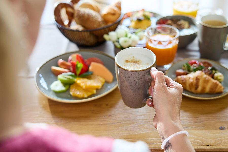Eine Frau genießt ihren Morgenkaffee am Frühstückstisch