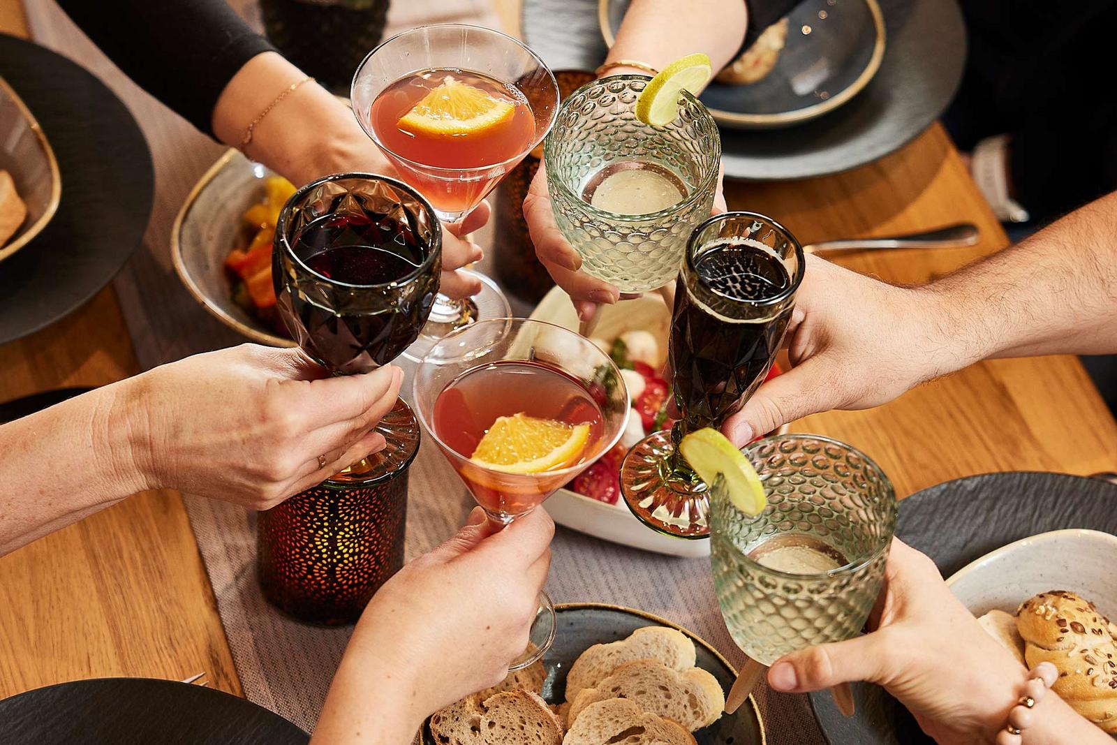 mehrere Personen stoßen mit verschiedenen Getränken an