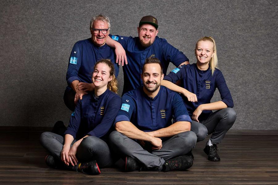 Ein Teil der Köche des Hotels lächeln herzlich in die Kamera