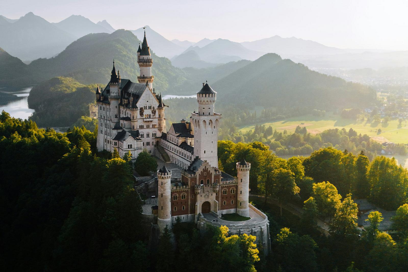 Drohnenaufnahme über das Schloss Neuschwanstein im Sonnenuntergang