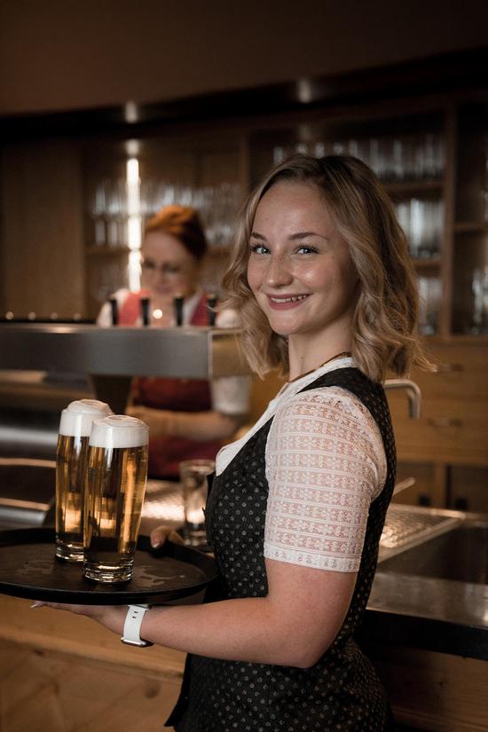 Eine junge Kellnerin lächelt in die Kamera