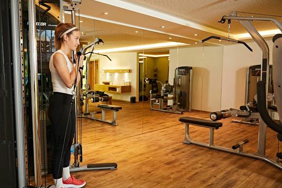Eine Frau trainiert im schönen Fitnessraum des Hotels