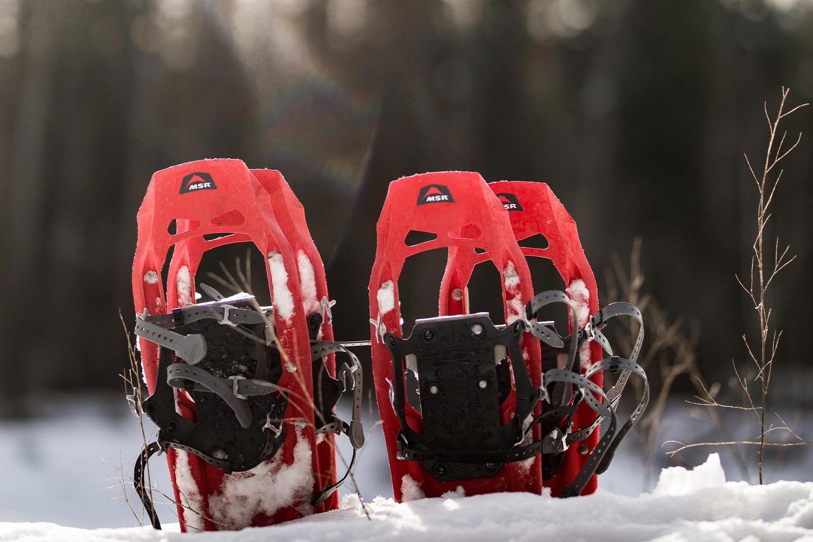 2 Paar rote Schneeschuhe stecken im Schnee
