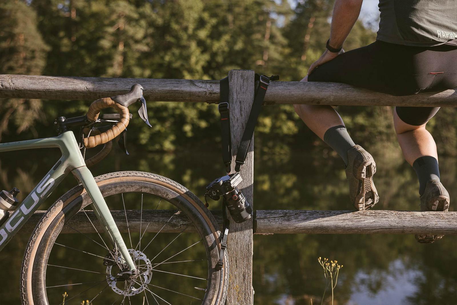 Ein Mann sitzt neben seinem Fahrrad auf einem Holzzaun