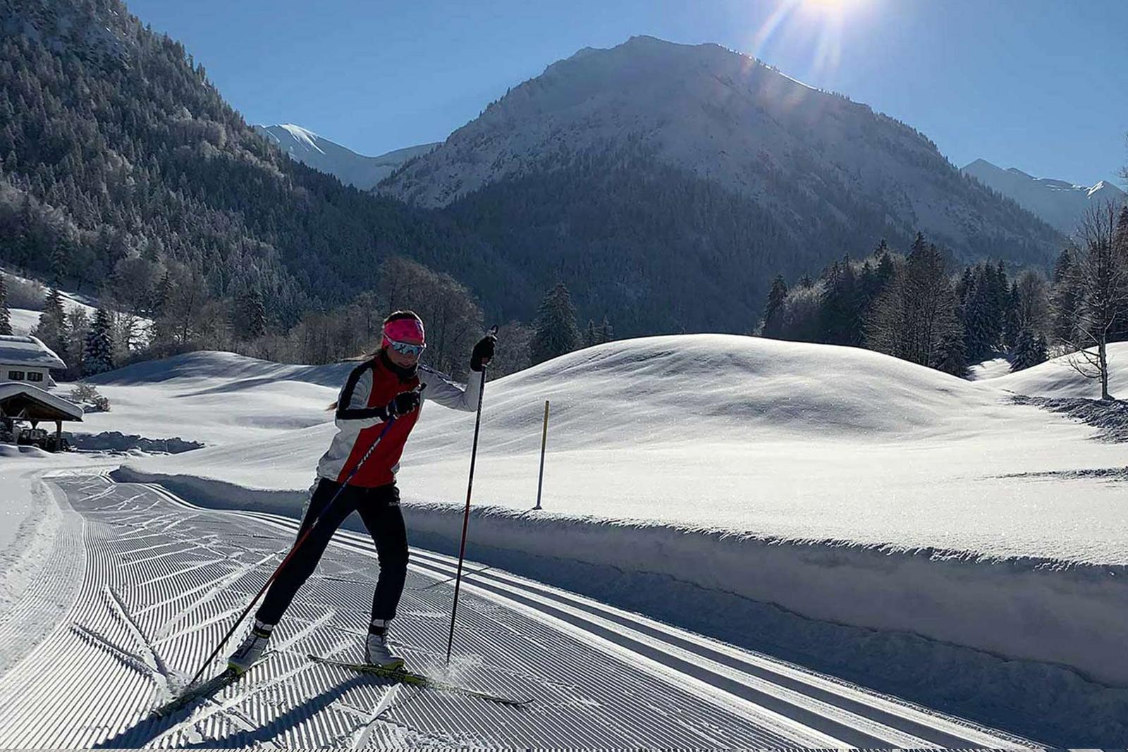 Eine Langlaufloipe mit Langlöuer bei strahlendem Sonnenschein