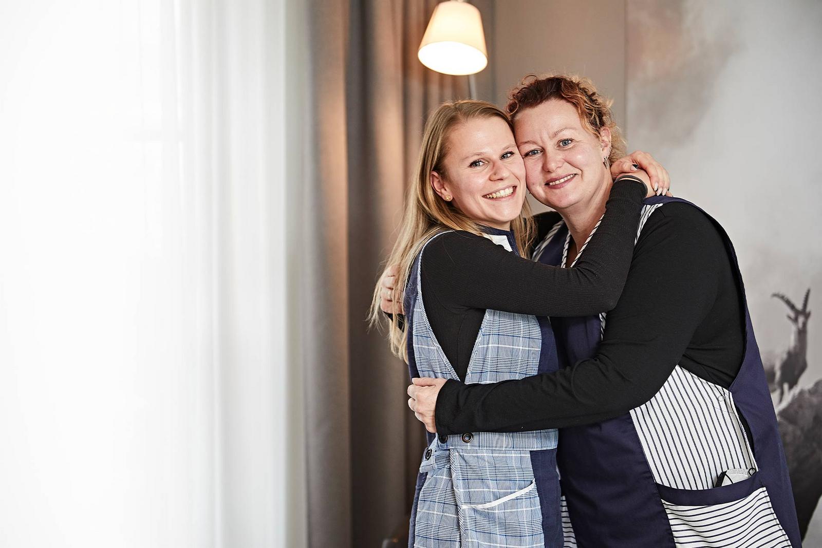 Zwei Damen des Housekeeping umarmen sich innig und lachen herzlich in die Kamera