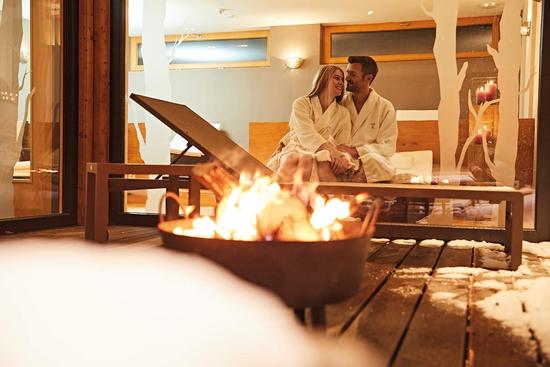 Ein Paar sitzt im Außenbereich des Spabereichs an einer Feuerschale