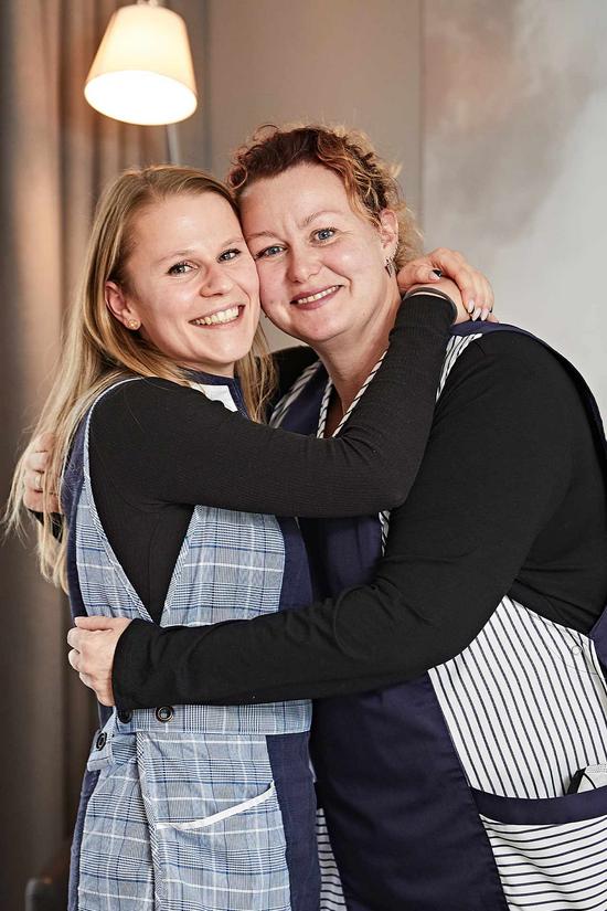 Zwei Mitarbeiterinnen des Housekeepings umarmen sich innig und lächeln in die Kamera