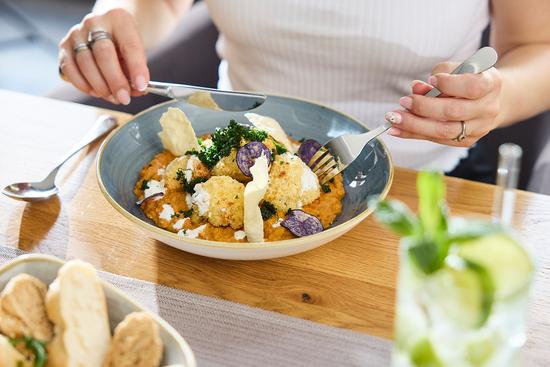 eine Frau genießt ein leckeres Linsen-Blumenkohl Gericht mit frischem Baguette