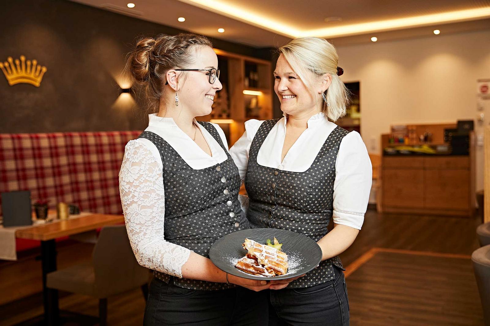 Zwei Servicekräft des Restaurants lachen sich herzlich an