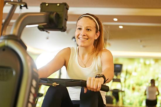 Eine junge Frau trainiert an einem Rudergerät im Fitnessraum des Hotels