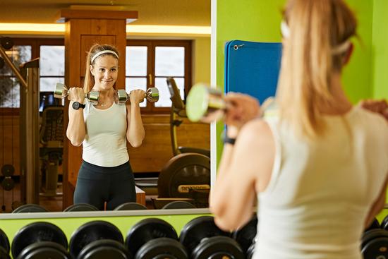 Eine junge Frau trainiert im Freihantelbereich des Fitnessbereichs im Hotel