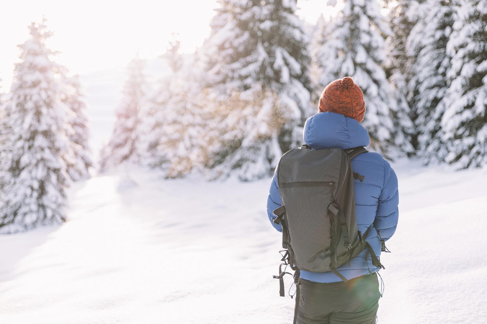 Ein Winterwanderer steht vor verschneiter Winterlandschaft