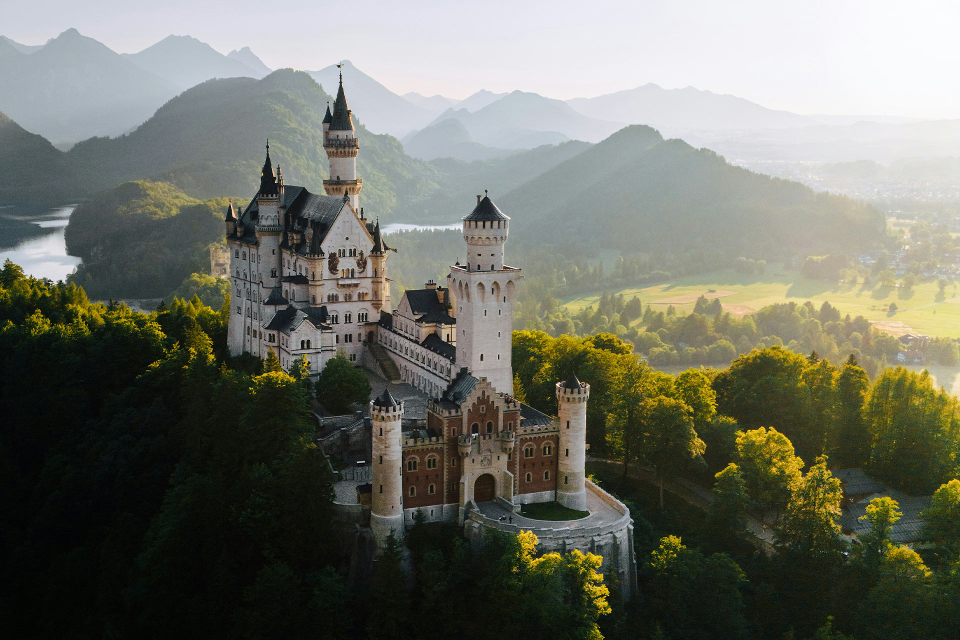 Drohnenaufnahme über das Schloss Neuschwanstein im Sonnenuntergang