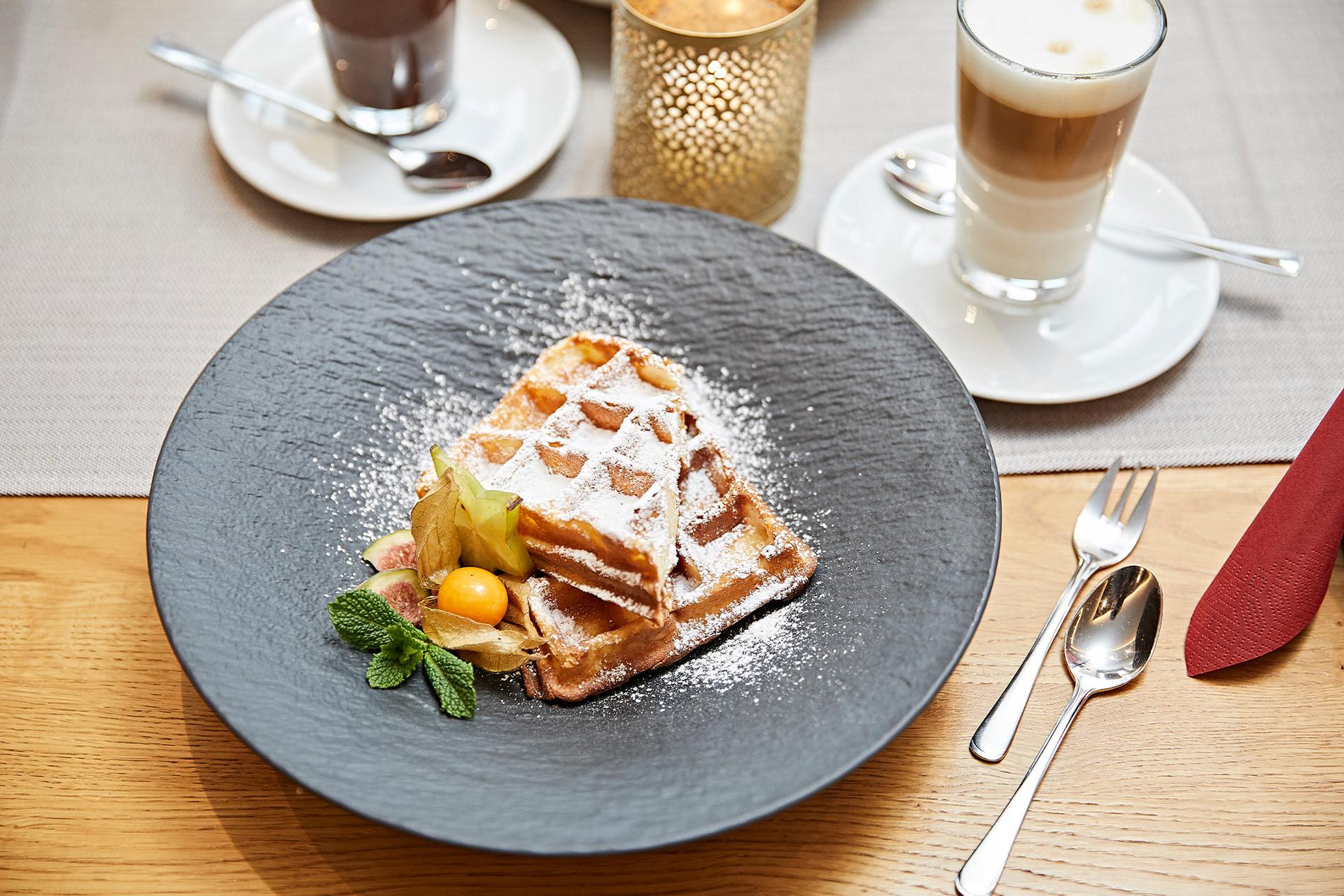 Bild einer mit Puderzucker garnierten belgischen Waffel auf einem Schieferteller