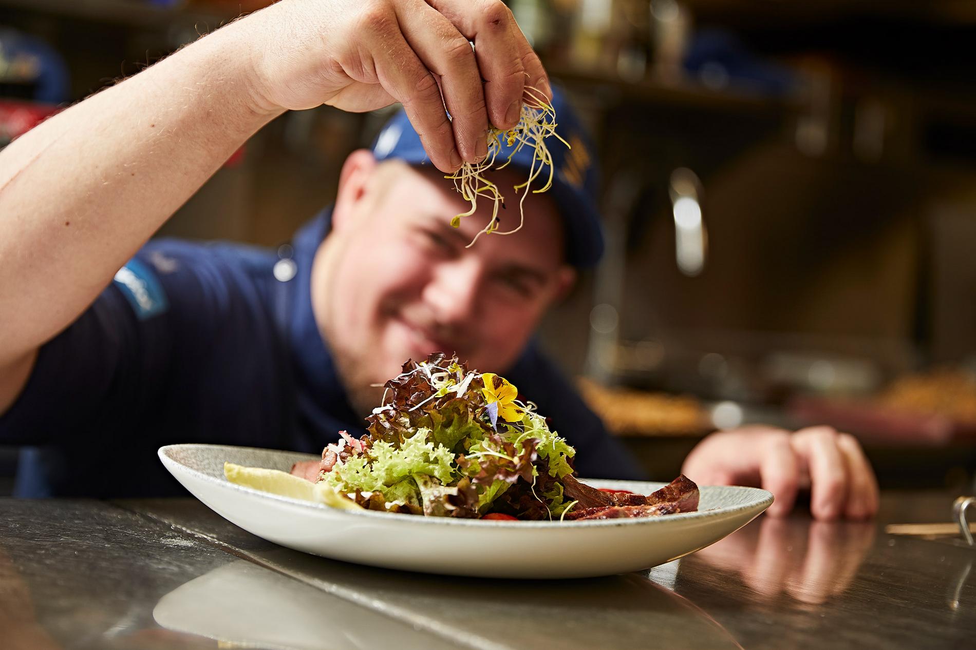 Ein Koch garniert einen Salat