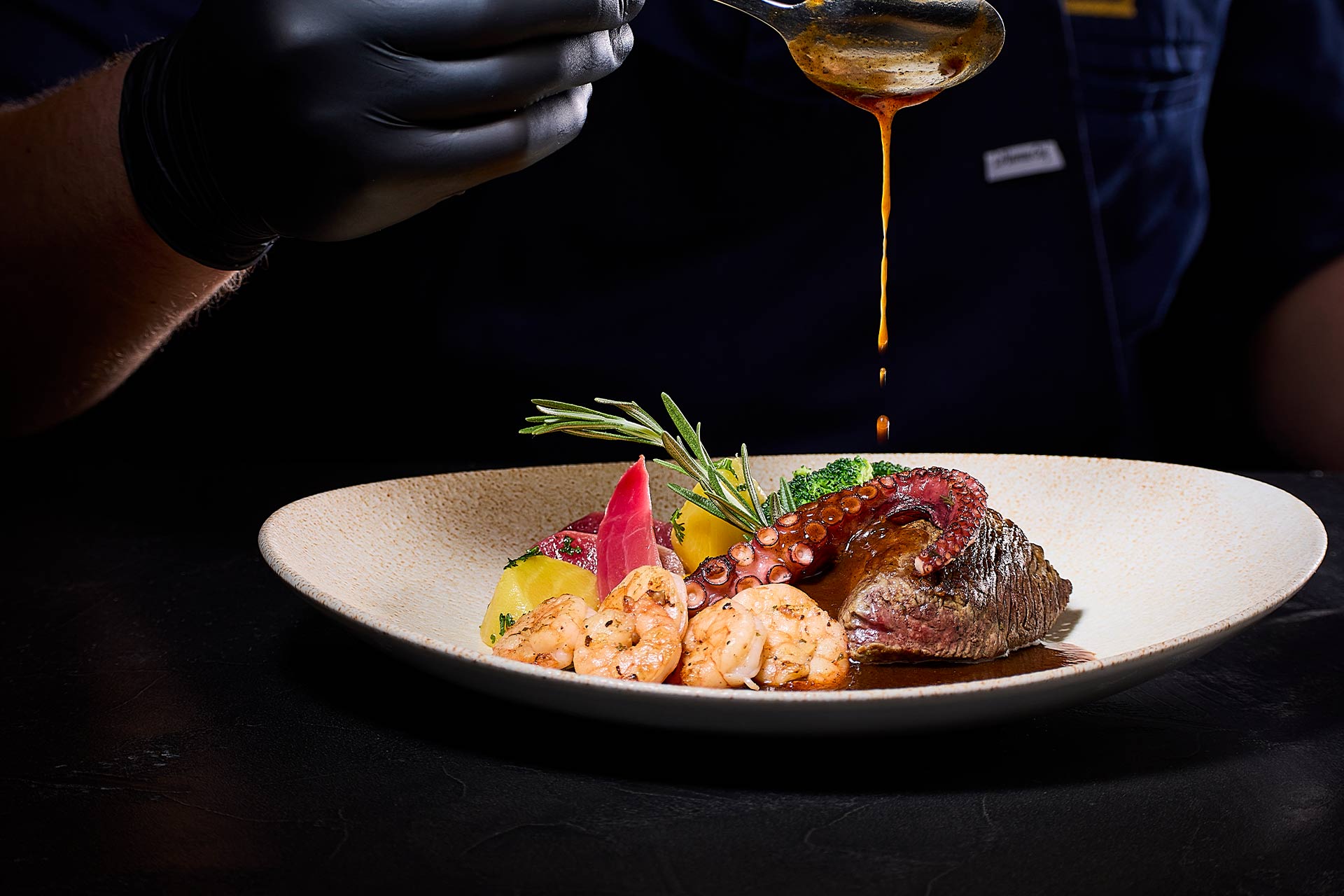 Ein Koch garniert ein frisches Gericht mit Sauce