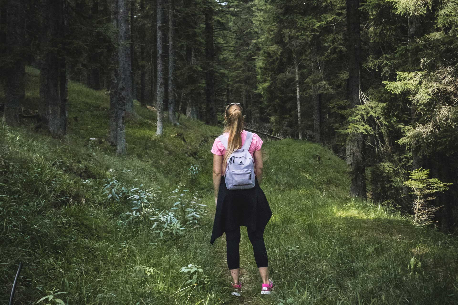 Eine junge Frau steht mit einem Rucksack auf dem Rücken im Wald
