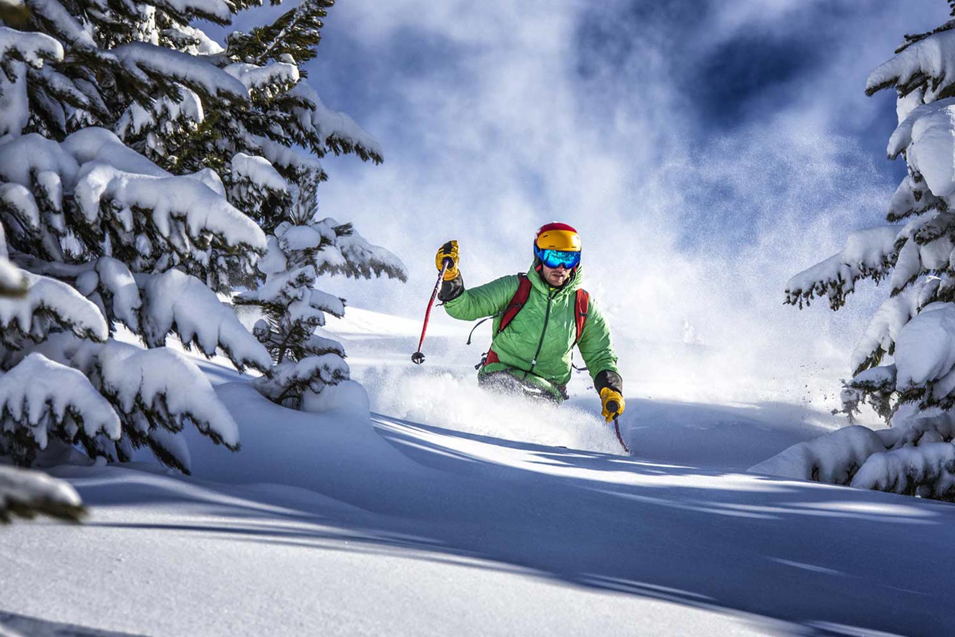 Ein Skifahrer fährt bei blauem Himmel durch Tiefschnee