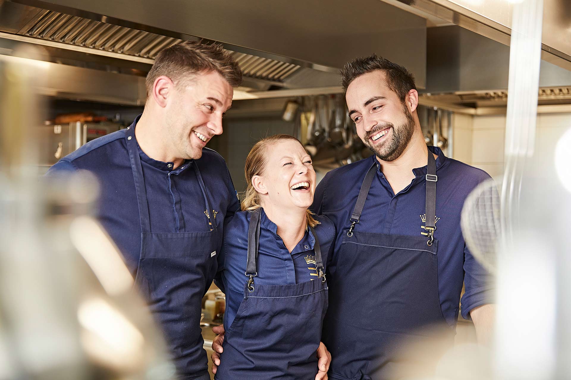 drei Köche stehen in der Küche und lachen sich herzlich an